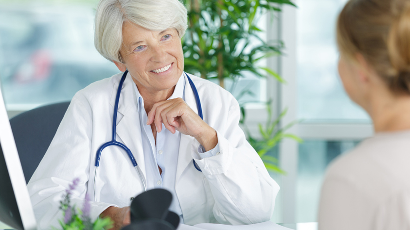 Woman doctor by desk with patient